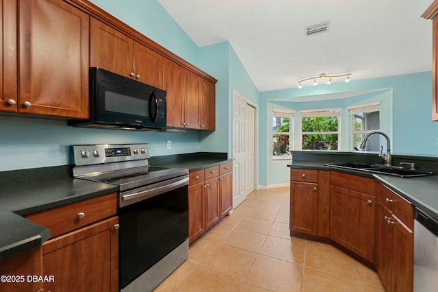 kitchen featuring appliances with stainless steel finishes, light tile patterned floors, lofted ceiling, and sink