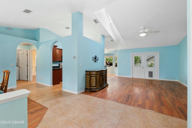 living room with ceiling fan, light tile patterned flooring, and vaulted ceiling