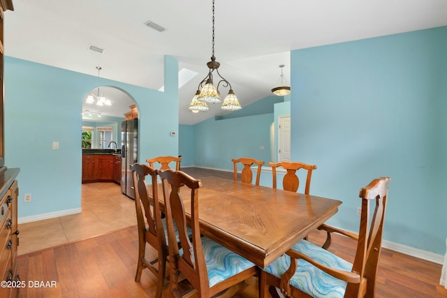 dining room with sink, light hardwood / wood-style floors, and lofted ceiling