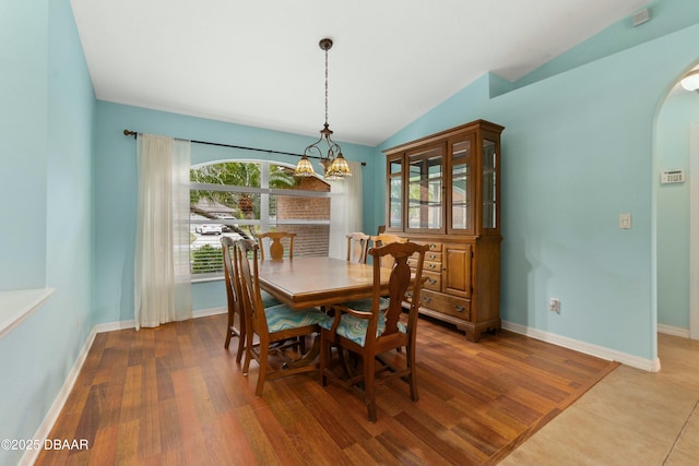 dining space with a chandelier, wood-type flooring, and vaulted ceiling