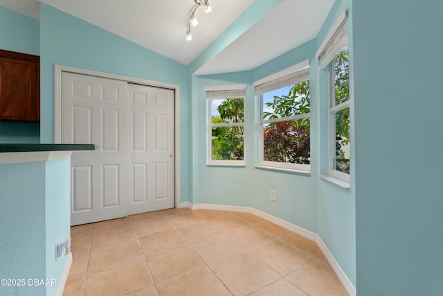 unfurnished bedroom with a closet, lofted ceiling, and light tile patterned flooring