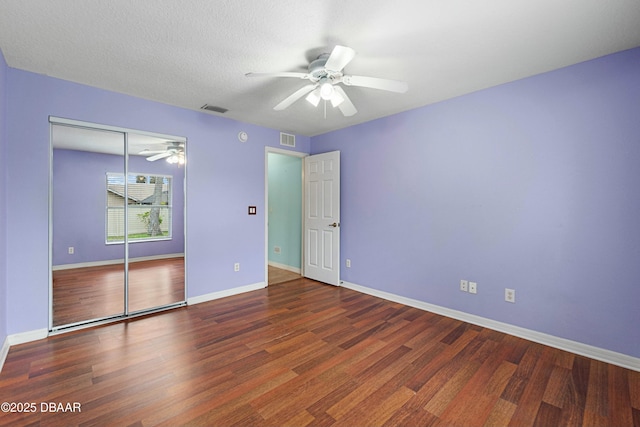 unfurnished bedroom with ceiling fan, dark hardwood / wood-style flooring, a textured ceiling, and a closet