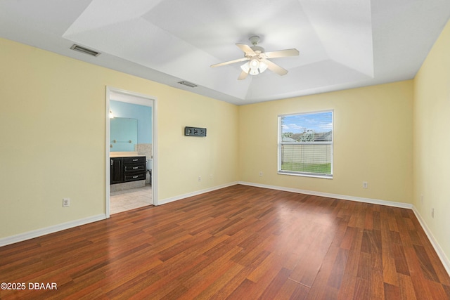 empty room with wood-type flooring, a raised ceiling, and ceiling fan