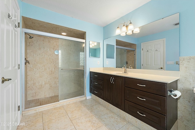 bathroom with a shower with door, vanity, and tile patterned flooring