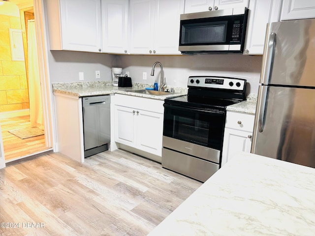 kitchen featuring white cabinets, sink, light hardwood / wood-style flooring, appliances with stainless steel finishes, and light stone counters