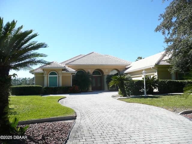 mediterranean / spanish home with a garage and a front lawn