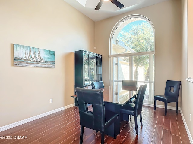 dining room with ceiling fan, dark hardwood / wood-style floors, and a towering ceiling