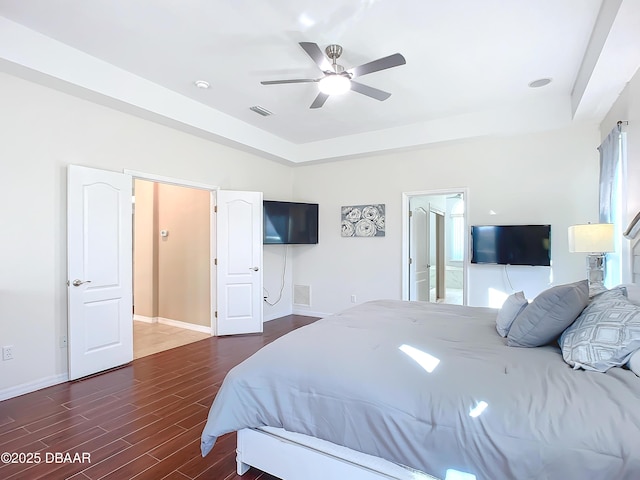 bedroom with ceiling fan, dark wood-type flooring, and a raised ceiling