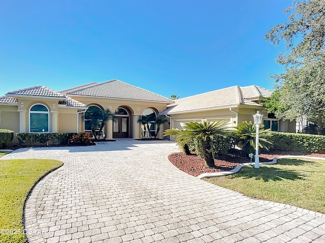 mediterranean / spanish home featuring a garage and a front yard