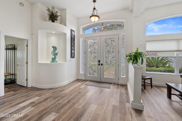 foyer with a towering ceiling, french doors, and hardwood / wood-style flooring