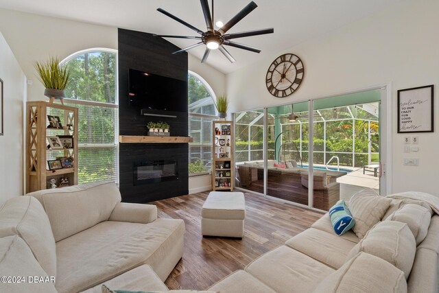 living room featuring lofted ceiling, a fireplace, light wood-type flooring, and ceiling fan