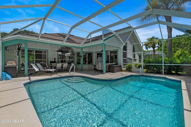 view of pool with ceiling fan, glass enclosure, and a patio area