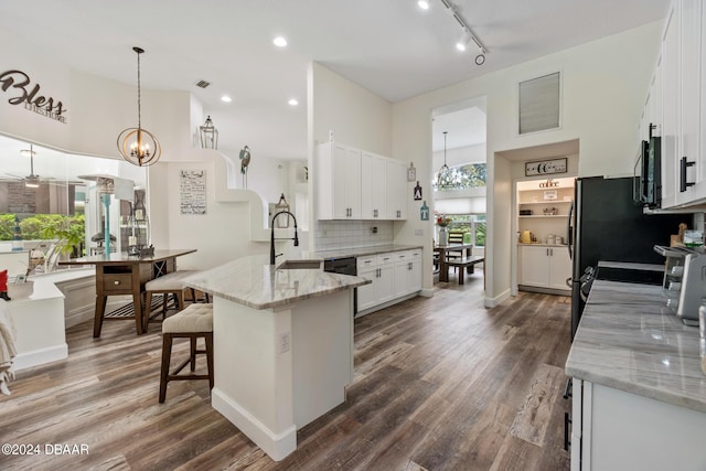 kitchen featuring sink, white cabinetry, light stone countertops, dark hardwood / wood-style flooring, and pendant lighting