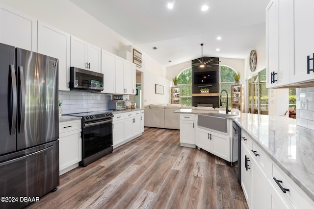 kitchen with lofted ceiling, stainless steel appliances, white cabinets, and tasteful backsplash