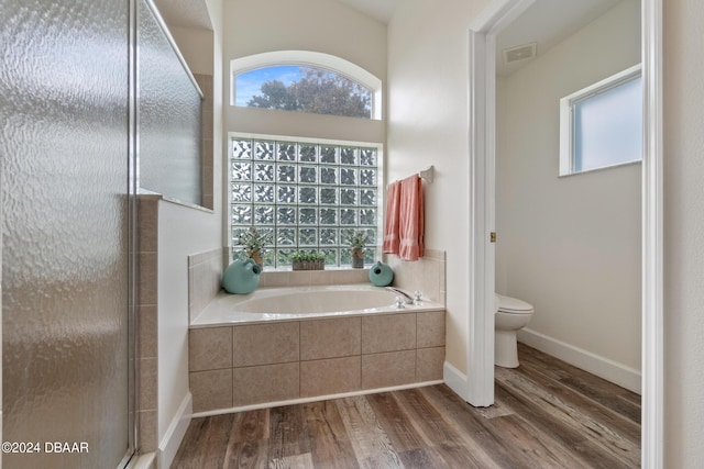 bathroom with toilet, plus walk in shower, and hardwood / wood-style floors