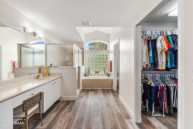 bathroom with a textured ceiling, lofted ceiling, hardwood / wood-style flooring, vanity, and plus walk in shower