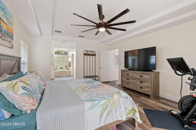 bedroom with ensuite bathroom, a textured ceiling, ceiling fan, and hardwood / wood-style flooring