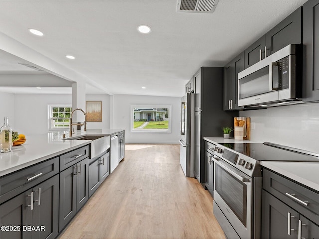 kitchen with visible vents, a sink, stainless steel appliances, recessed lighting, and light wood-style flooring