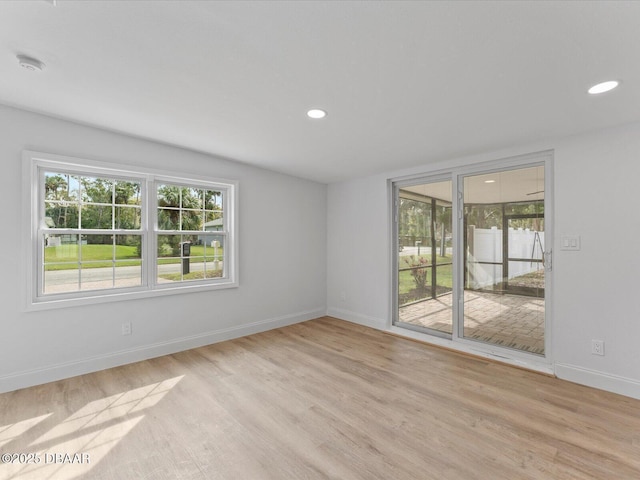 spare room featuring a healthy amount of sunlight, baseboards, recessed lighting, and light wood-style flooring