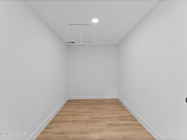 spare room featuring visible vents, attic access, light wood finished floors, and baseboards