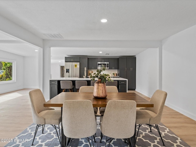dining room with recessed lighting, baseboards, visible vents, and light wood finished floors