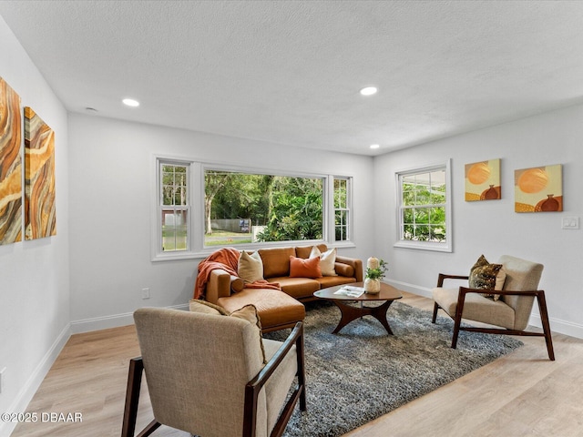 living area featuring recessed lighting, baseboards, light wood-type flooring, and a textured ceiling