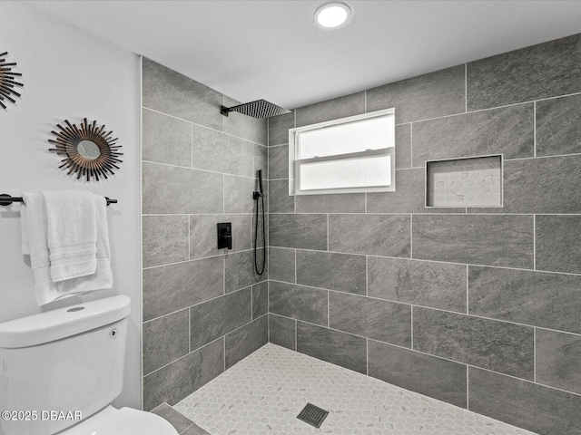 full bathroom featuring a tile shower and toilet