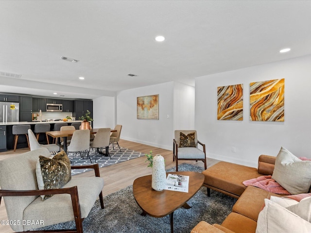 living area with recessed lighting, baseboards, visible vents, and light wood-style floors