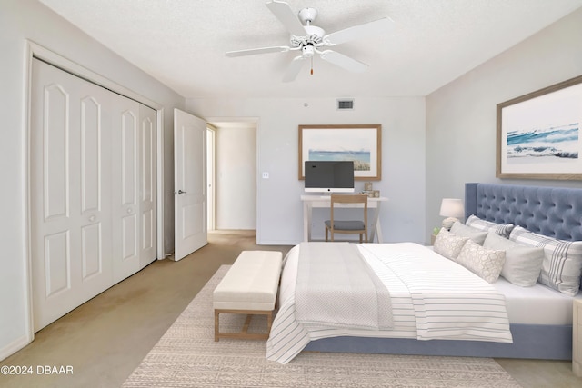 bedroom featuring a closet, a textured ceiling, light colored carpet, and ceiling fan