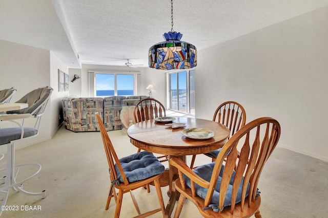 dining room with ceiling fan, a textured ceiling, and light colored carpet