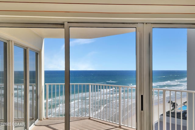 unfurnished sunroom featuring a beach view, a water view, and plenty of natural light