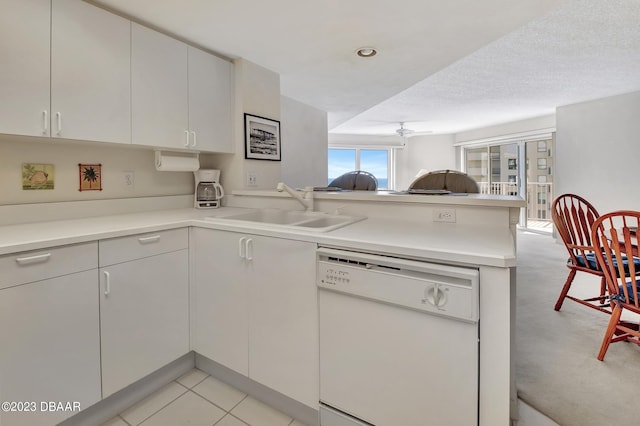 kitchen featuring sink, kitchen peninsula, white dishwasher, ceiling fan, and light colored carpet