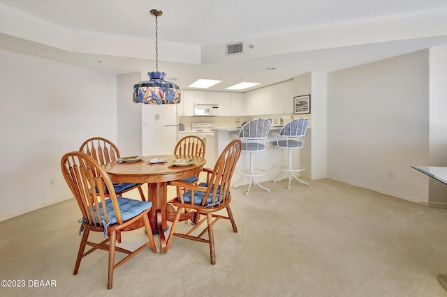 dining space featuring a textured ceiling and light carpet