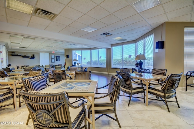 dining area featuring a paneled ceiling, a healthy amount of sunlight, and light tile patterned floors