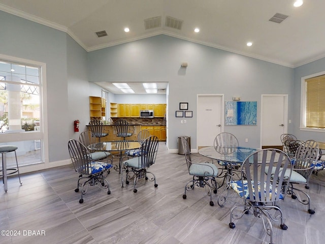 dining space featuring high vaulted ceiling and ornamental molding