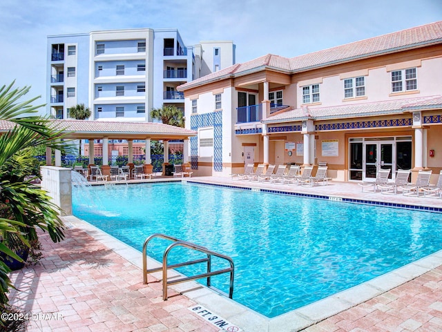 view of pool featuring pool water feature and a patio