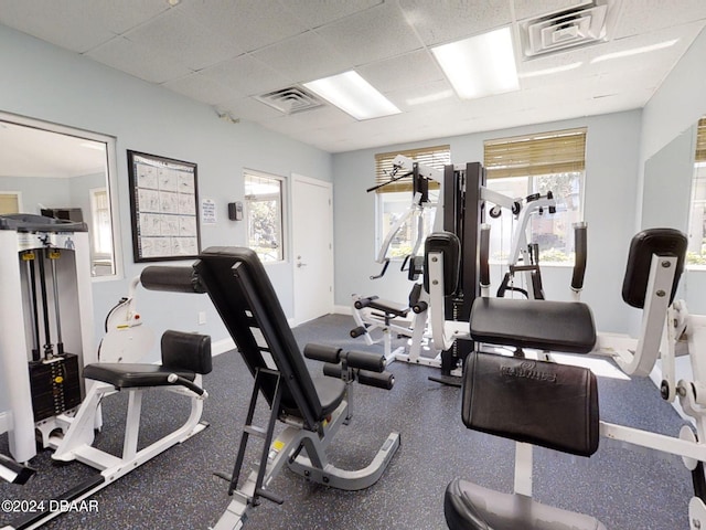 workout area with a paneled ceiling and a healthy amount of sunlight