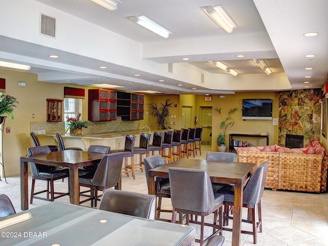 tiled dining room with a stone fireplace