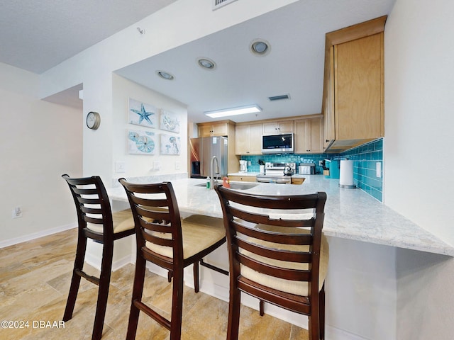 kitchen featuring appliances with stainless steel finishes, backsplash, light brown cabinets, and sink