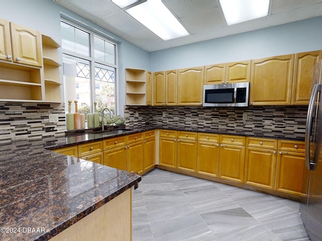 kitchen with decorative backsplash, dark stone countertops, sink, and appliances with stainless steel finishes