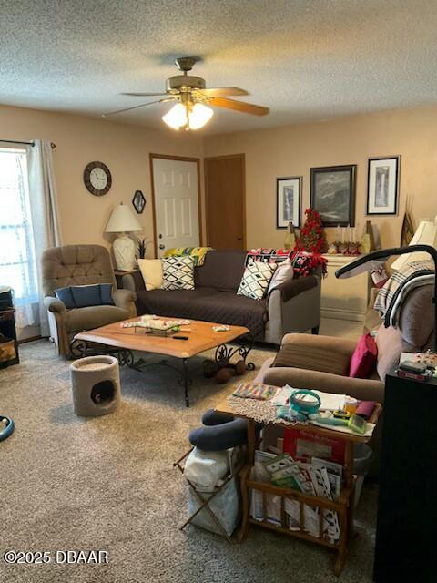 carpeted living room with ceiling fan and a textured ceiling