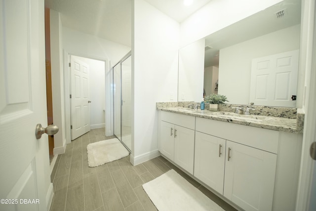 full bath with wood finish floors, visible vents, a sink, and a shower stall