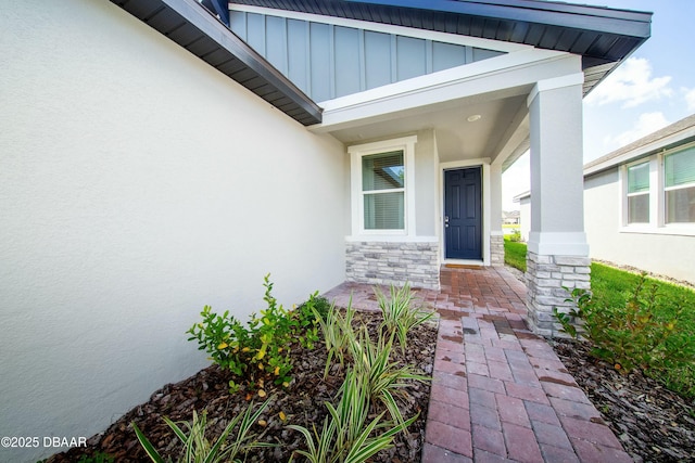 doorway to property with stone siding, board and batten siding, and stucco siding