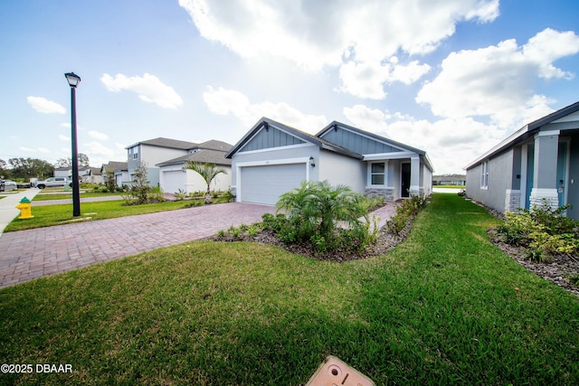 view of front of property featuring board and batten siding, a front yard, decorative driveway, and an attached garage