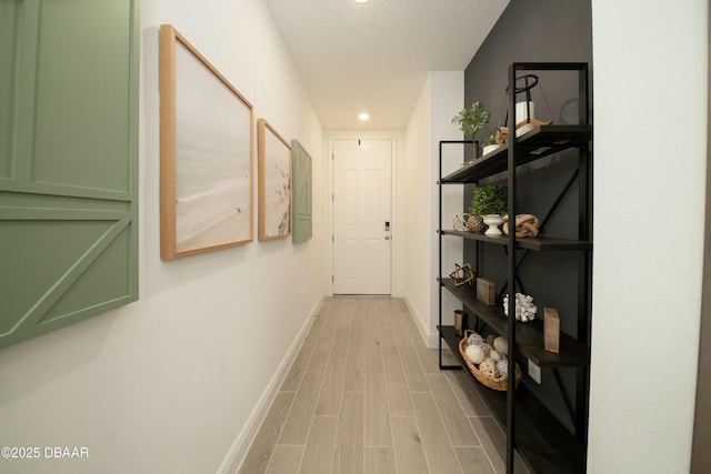 hallway with baseboards, recessed lighting, and light wood-style floors