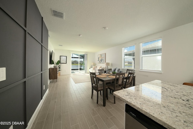 dining area featuring visible vents, a textured ceiling, and wood finished floors