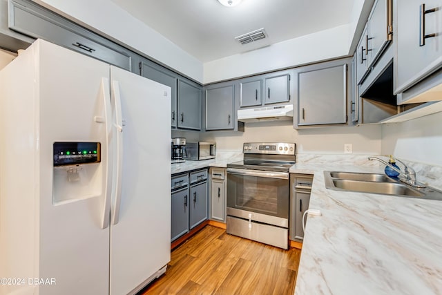 kitchen featuring stainless steel range with electric stovetop, sink, gray cabinets, light hardwood / wood-style floors, and white fridge with ice dispenser