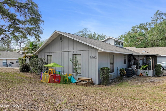 view of property exterior with a sunroom, central AC unit, and a yard