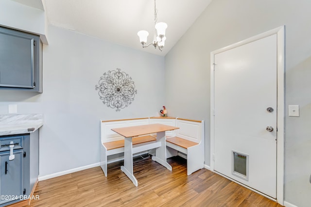 dining room with breakfast area, light hardwood / wood-style floors, vaulted ceiling, and a notable chandelier