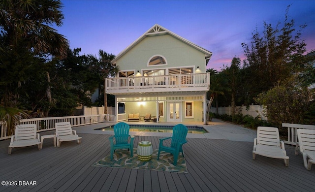 3110 John Anderson Dr, Ormond Beach, FL 32176 - back house at dusk featuring a balcony, a swimming pool side deck, an outdoor hangout area, and a patio area